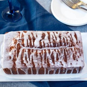 3/4 angle of a Champagne Pound Cake drizzled with a sugar glaze sitting on a white plate.