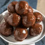 Side view of a stack of chocolate balls sitting on a white cake stand.