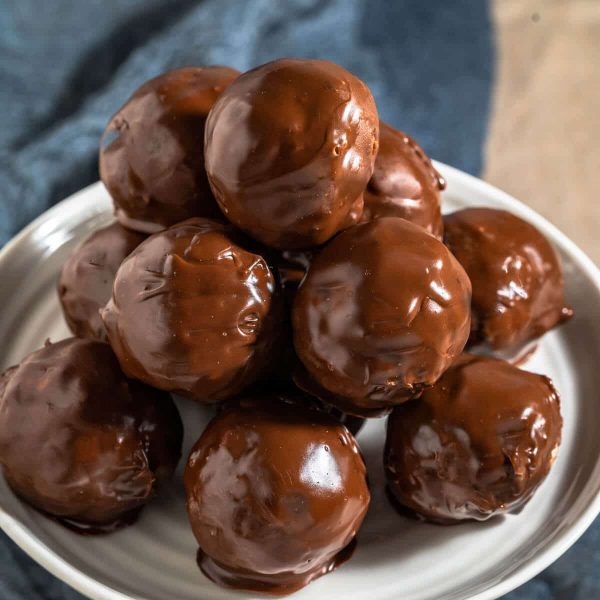 Side able of a stack of chocolate balls sitting on a white cake stand.