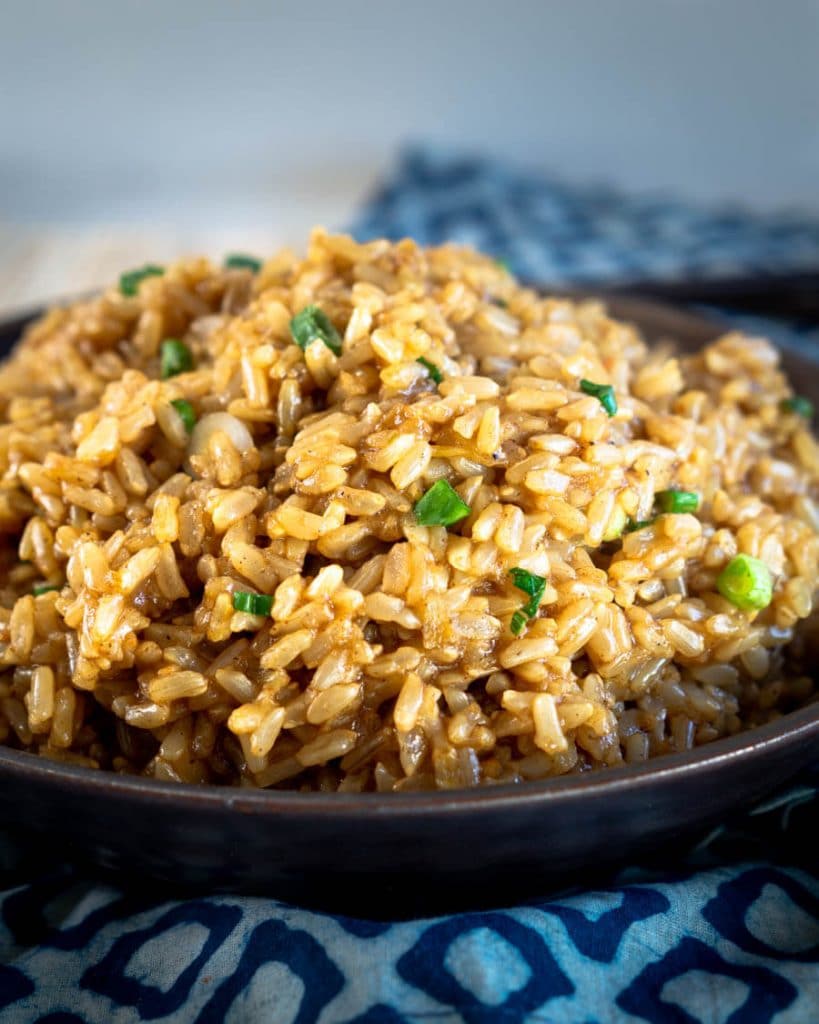 Side view of a bowl of Asian Brown Rice garnished with Green onion.