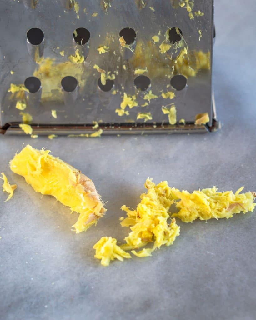 Grated fresh ginger sitting in front of a box grater.