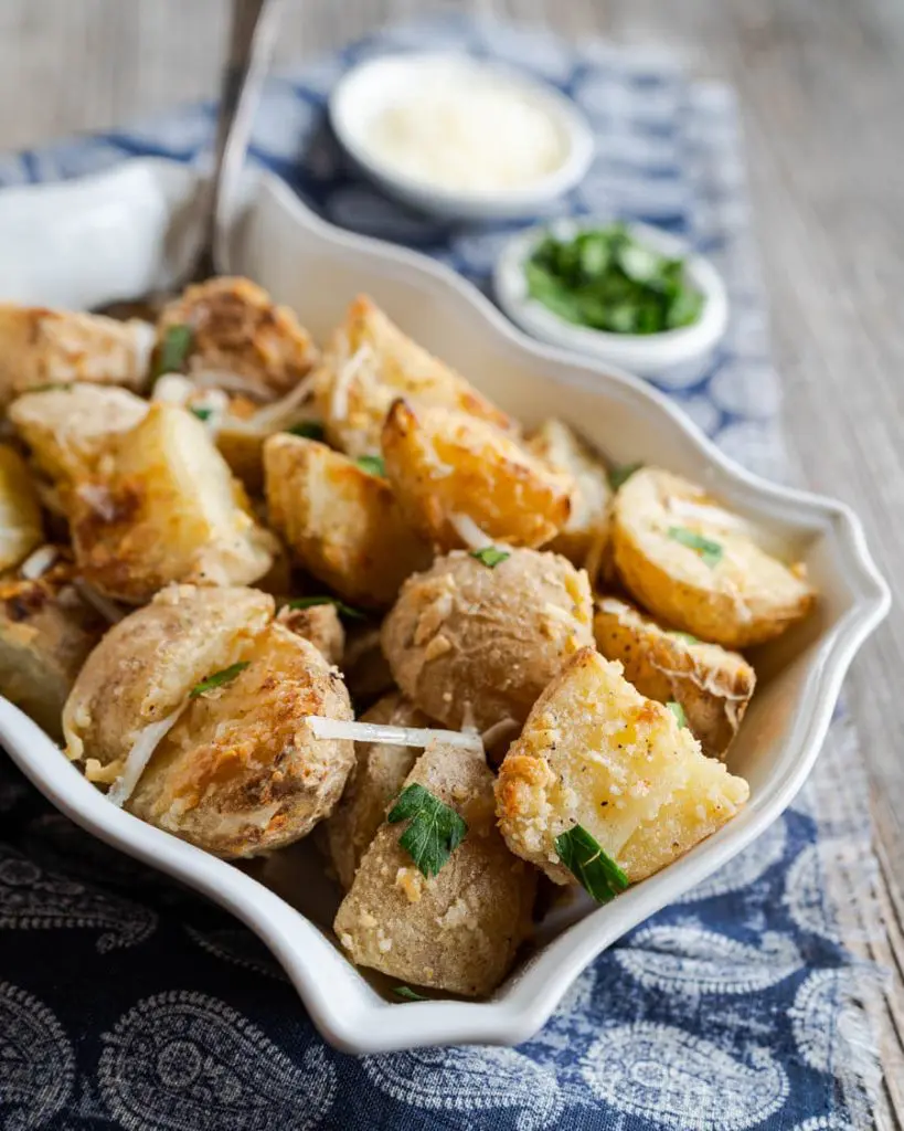 Side view of cheese crusted potatoes garnished with chopped parsley.