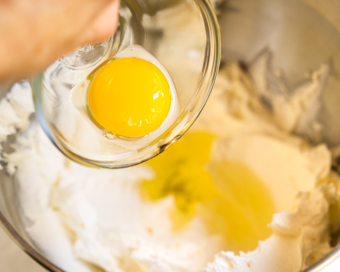Adding eggs to creamed sugar and butter in a mixing bowl
