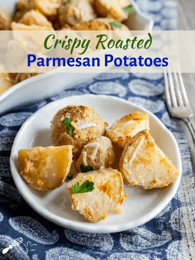 Top view of crispy roasted parmesan potatoes sitting on a plate with a baking dish of potatoes sitting in the background.