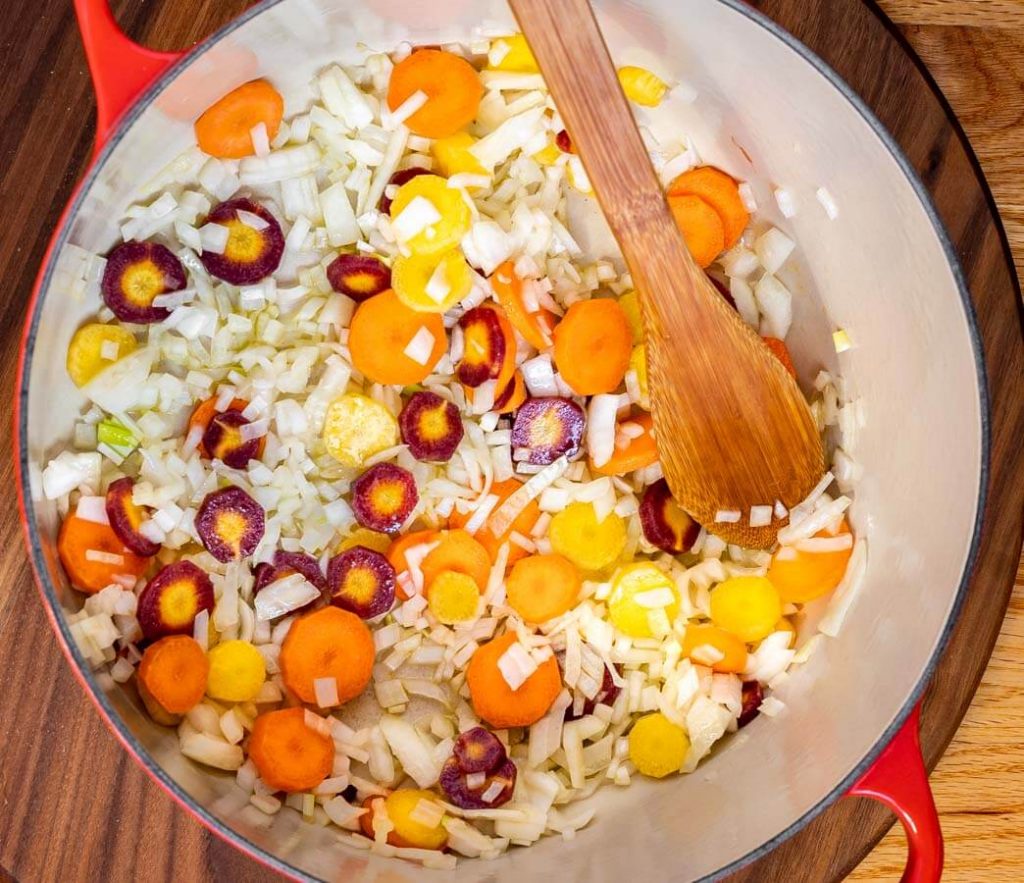 Top down view of a pot holding diced rainbow carrots and onions.