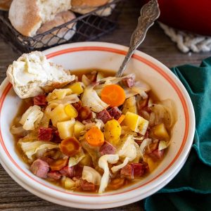 3/4 angle of a bowl of corned beef soup with cabbage, carrots, and potatoes.