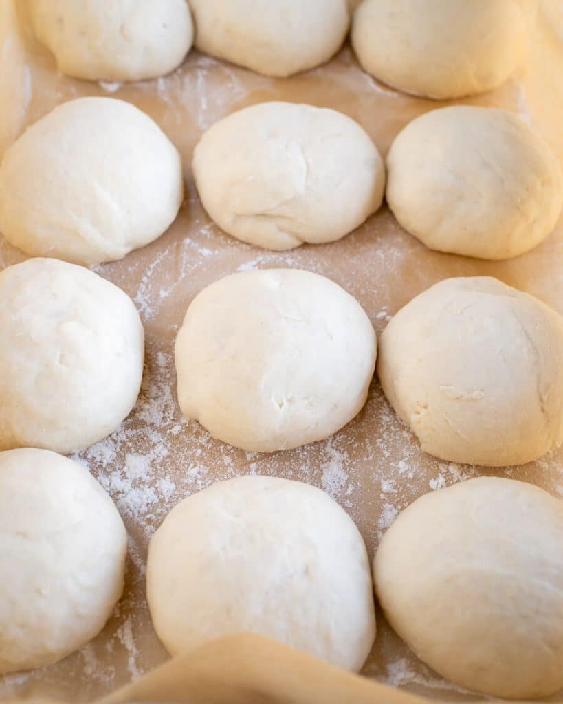 Shaped bread rolls rising in a pan.