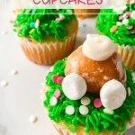 Cupcakes decorated with a grass tip with a bunny butt made from a donut hole sticking out.