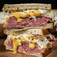 Corned Beef sandwich overloaded with sliced corned beef, mustard sauce and a cabbage slaw.