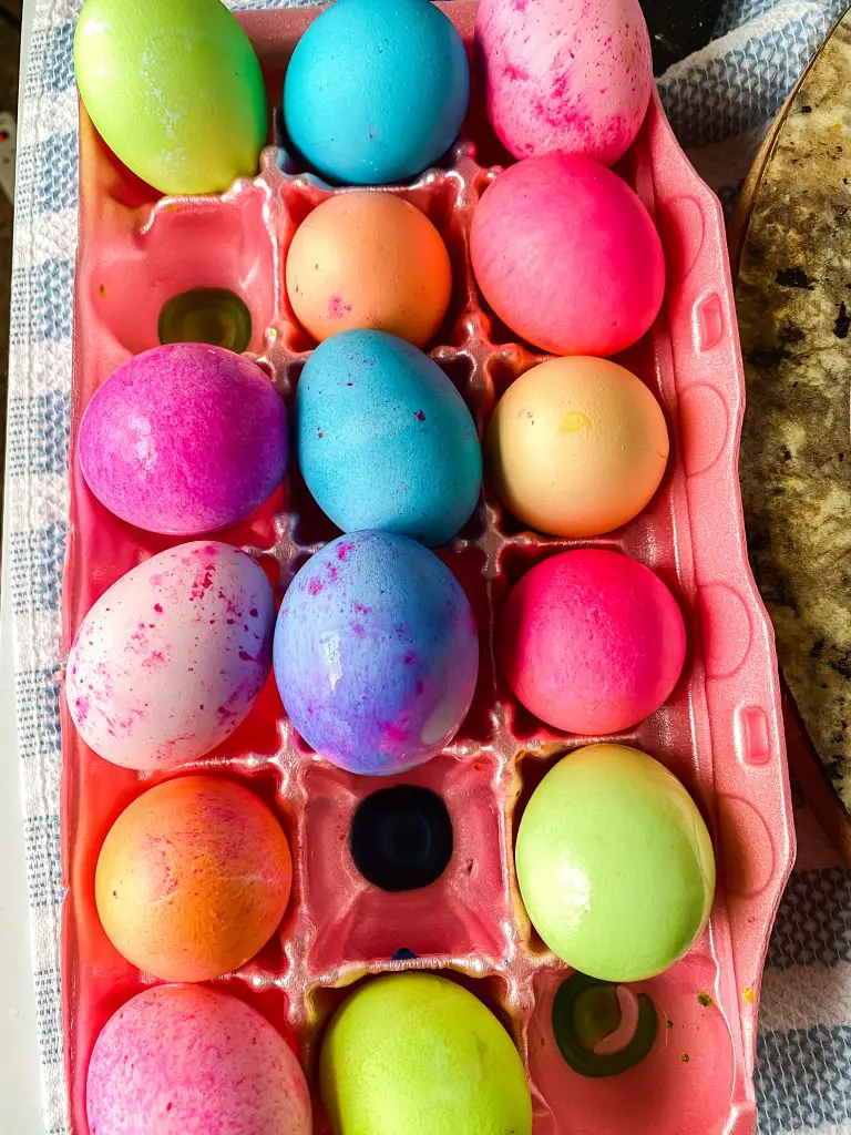 Multi-colored dyed eggs sitting in an egg carton.