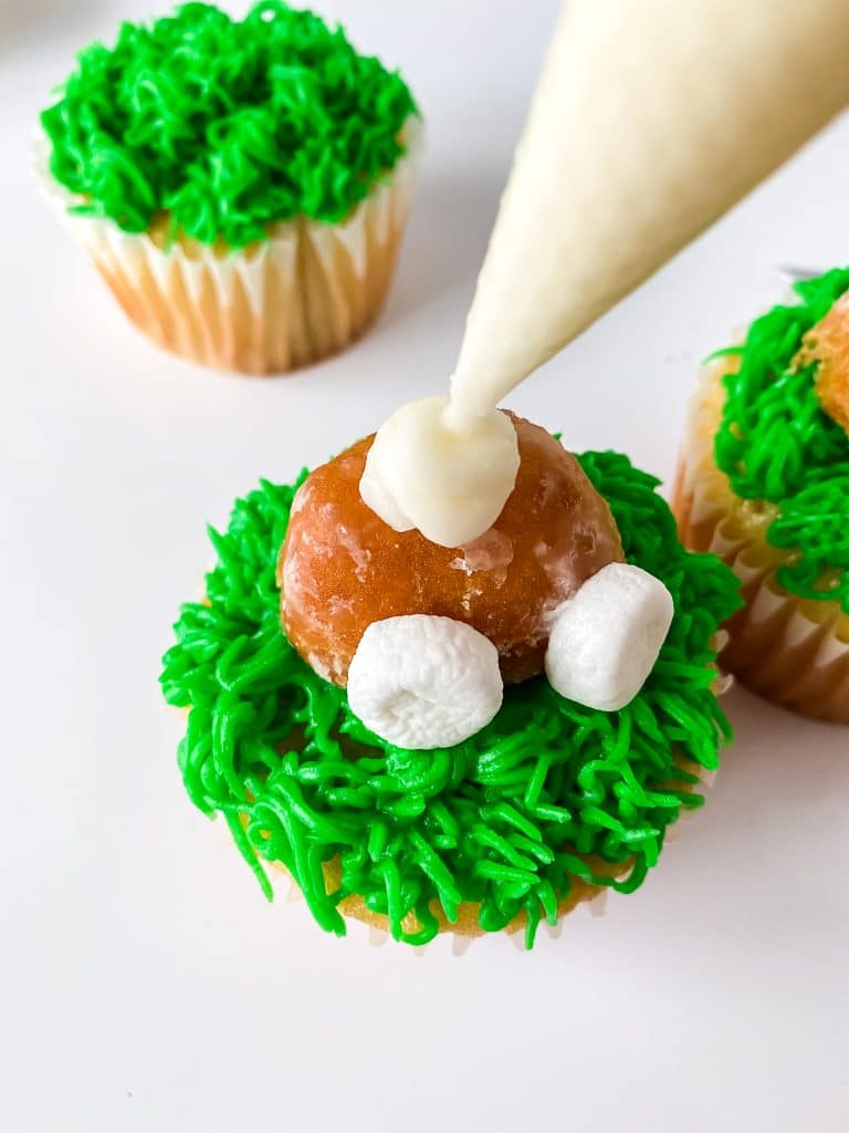 Piping the bunny's tail on a bunny cupcake.