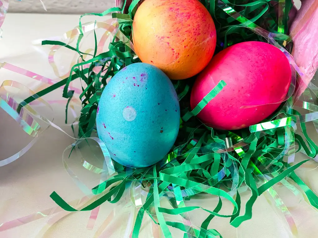 Colored boiled eggs sitting on shredded green paper