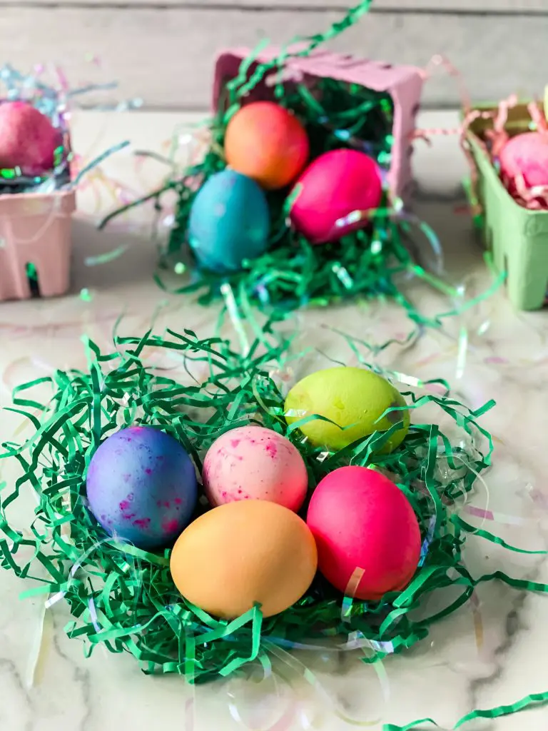 Multi-colored dyed Eggs sitting in shredded green paper