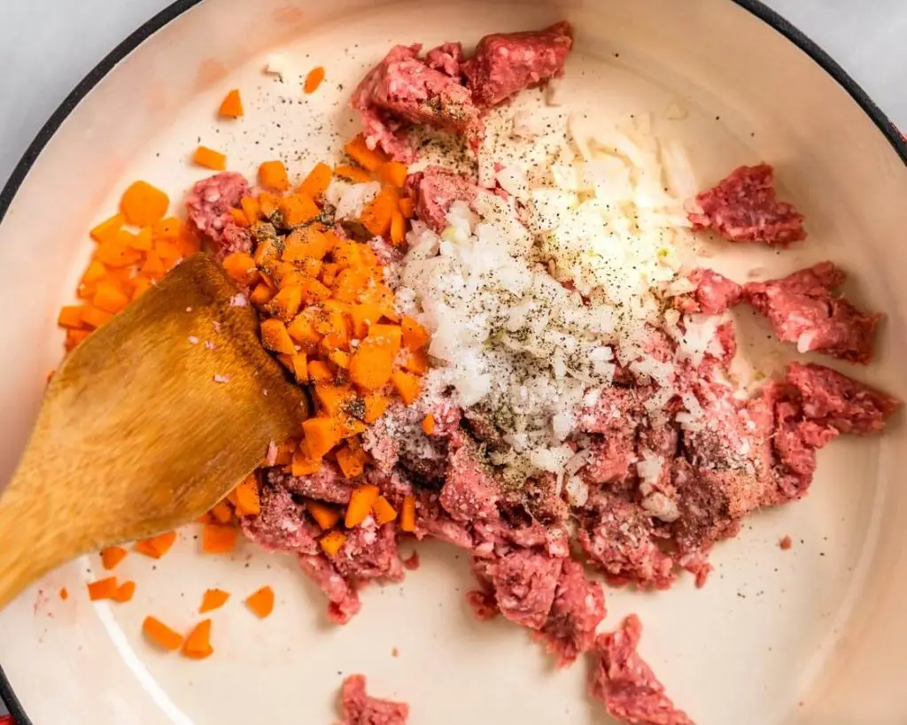 Ground meat, carrots, onion, salt and pepper cooking in a pan.