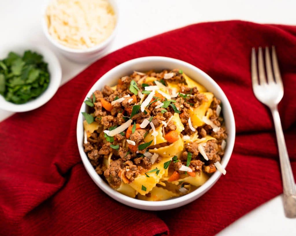 Top down shot of a bowl of pappardelle noodles and lamb bolognese sauce.