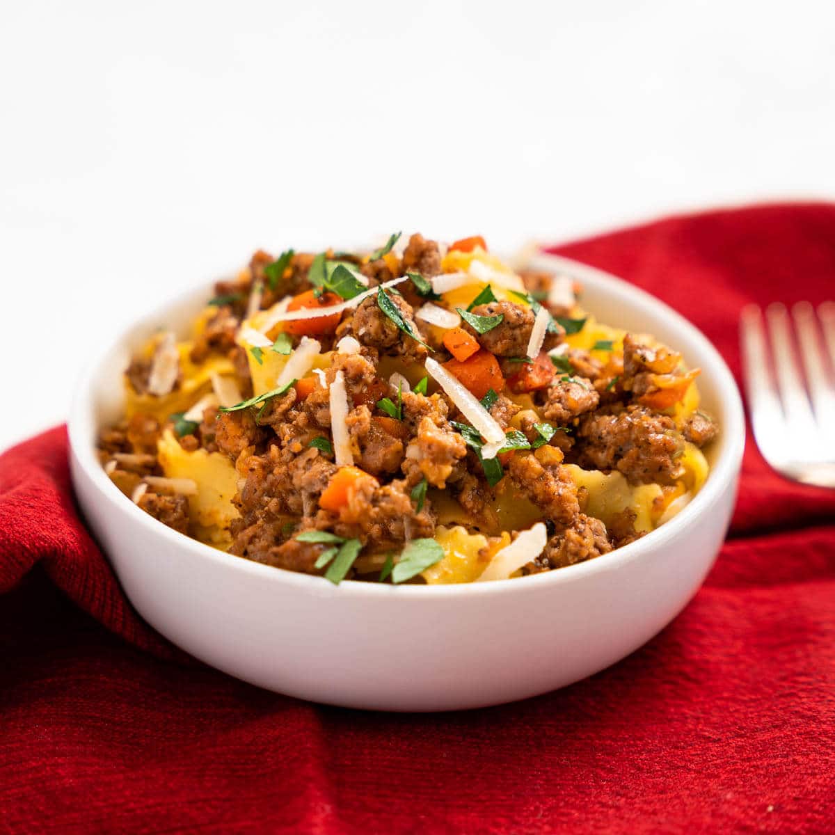 Tableview photo of a bowl of pappardelle noodles and meat sauce.