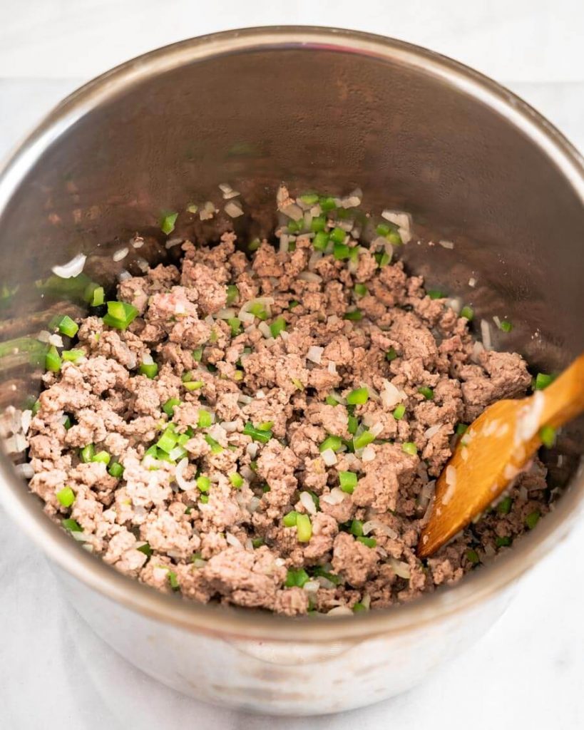 Browned ground meat with onion and green pepper in a pot.
