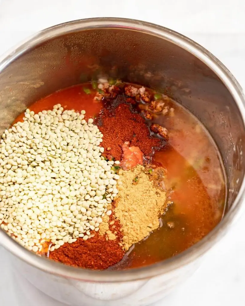Lentils, spices, and tomato juice in a pot.
