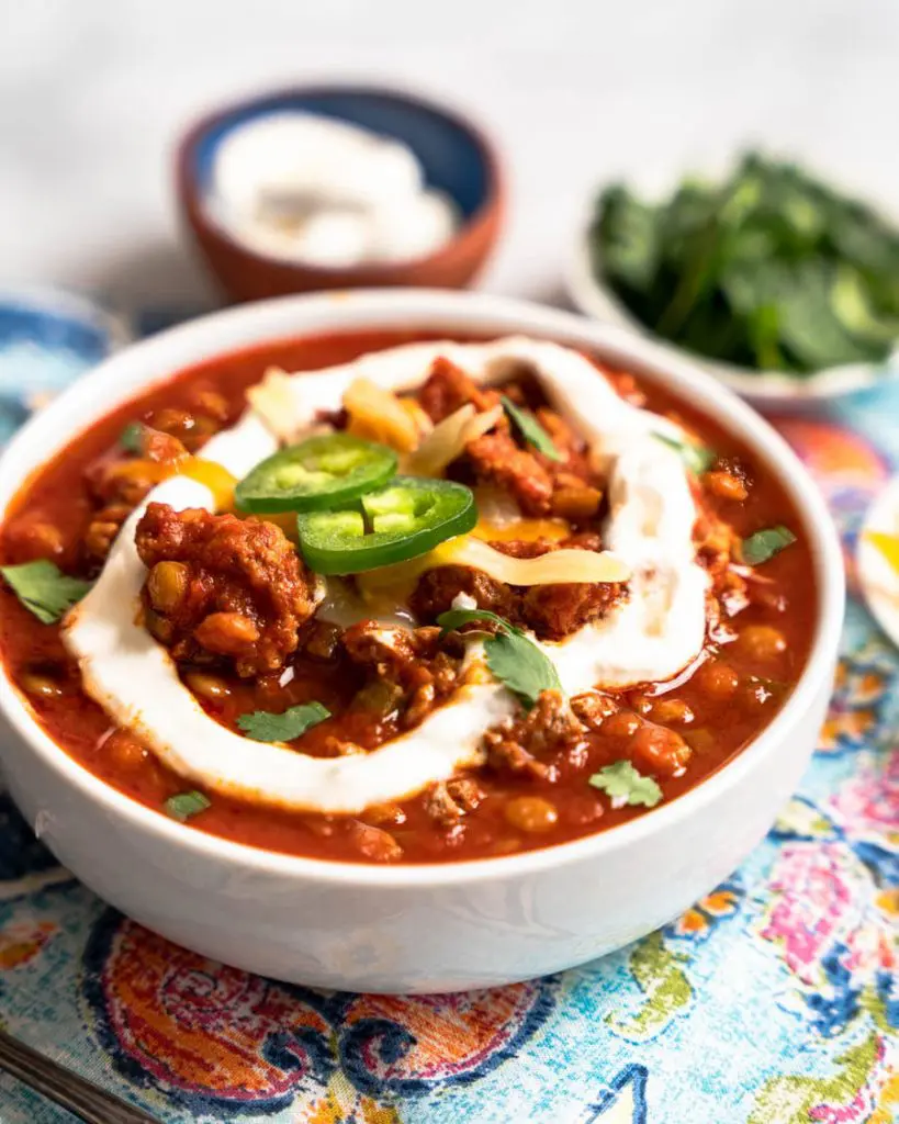 Close up of a bowl of lentil chili topped with sour cream and jalapenos