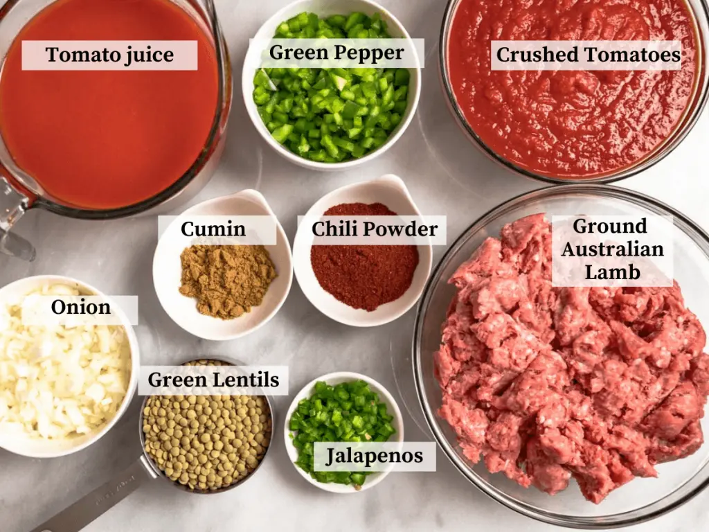 Top down view of ingredients including ground lamb, lentils, jalapenos, onions, green pepper, chili powder, cumin, tomato juice, and crushed tomatoes
