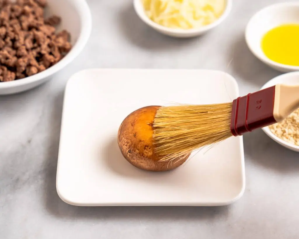A mushroom being brushed with olive oil.