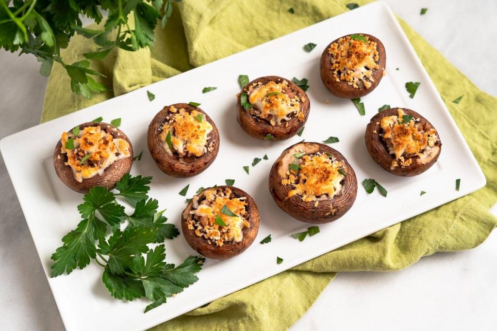 Top-down view of a white tray of cooked stuffed mushrooms.