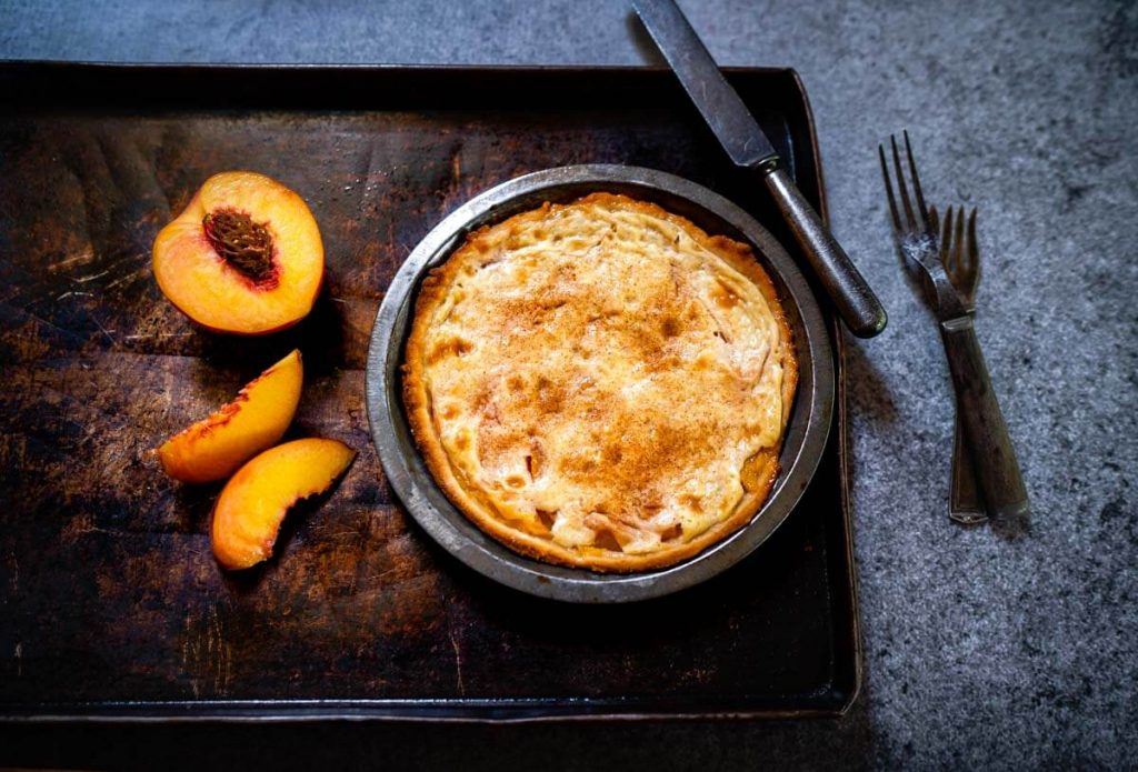 Top down photo of a Peach Kuchen Dessert in a pie tin.