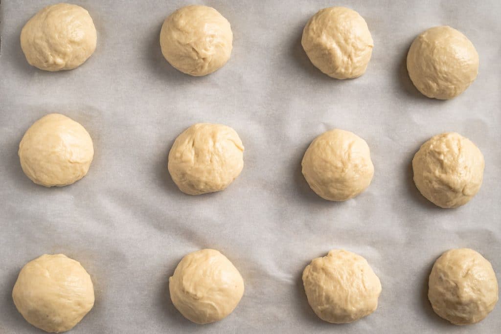 Shaped bread dough rolls on a baking sheet.