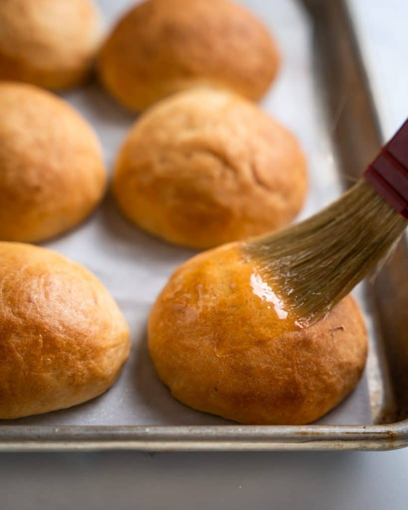 A bread roll being brushed with melted butter