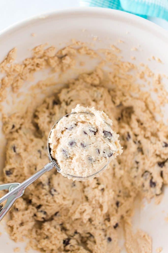 Cookie batter in a scoop hovering over the bowl