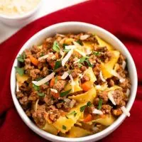 Top down shot of a bowl of pappardelle noodles and meat sauce.