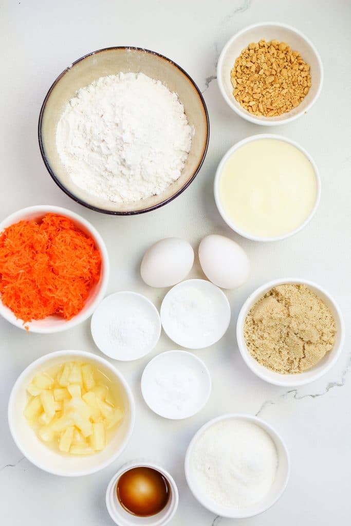Ingredients for cupcakes recipe: flour, sugar, brown sugar, baking powder, salt, eggs, pineapple, vanilla, grated carrots, chopped pecans.