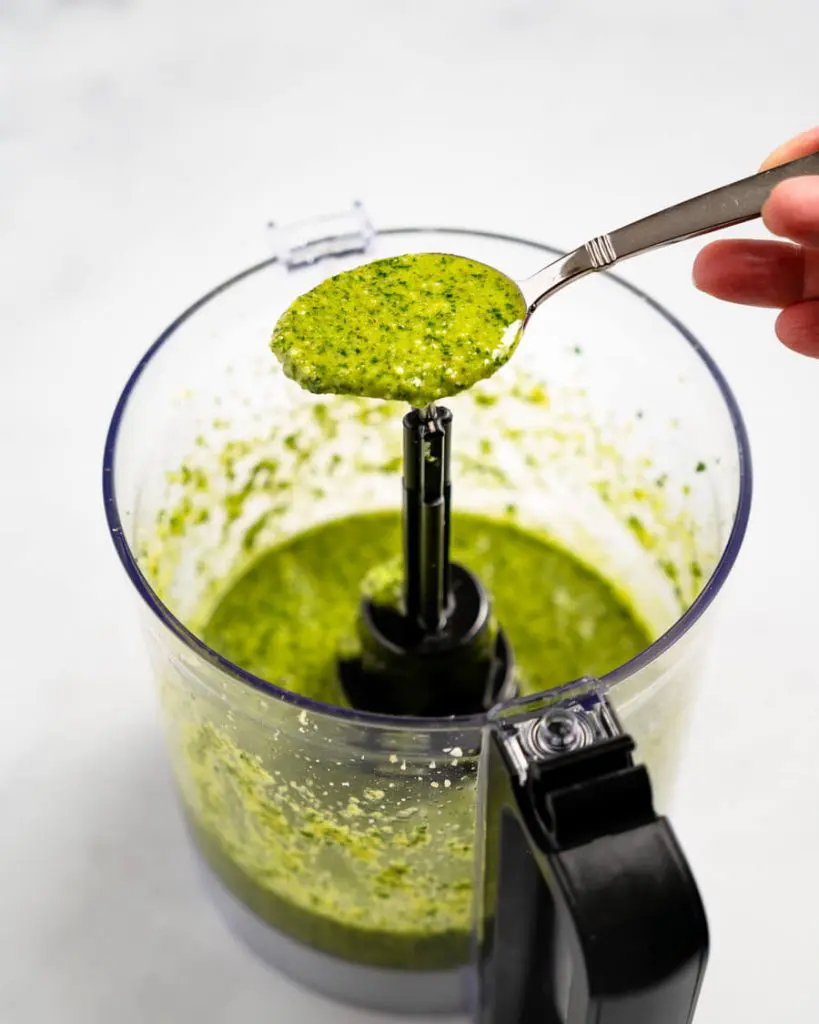 Spoonful of cilantro pesto sitting over a food processor