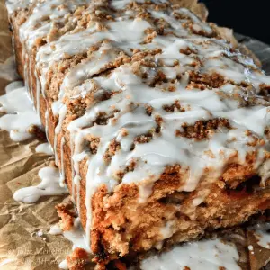 A loaf of strawberry rhubarb quick bread with streusel topping and glazed with icing.