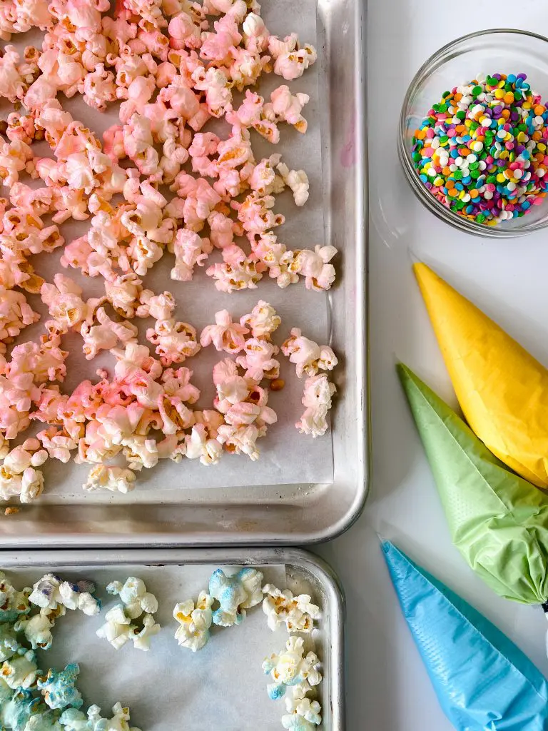 How to make unicorn popcorn. Steps demonstrated include spraying the popcorn pink, piping the chocolate.