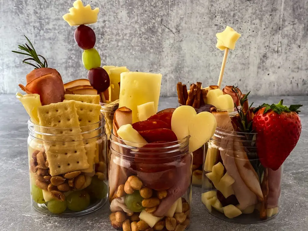 savory jarcuterie on a counter with crackers, cheese, meat, nuts, and fruit.