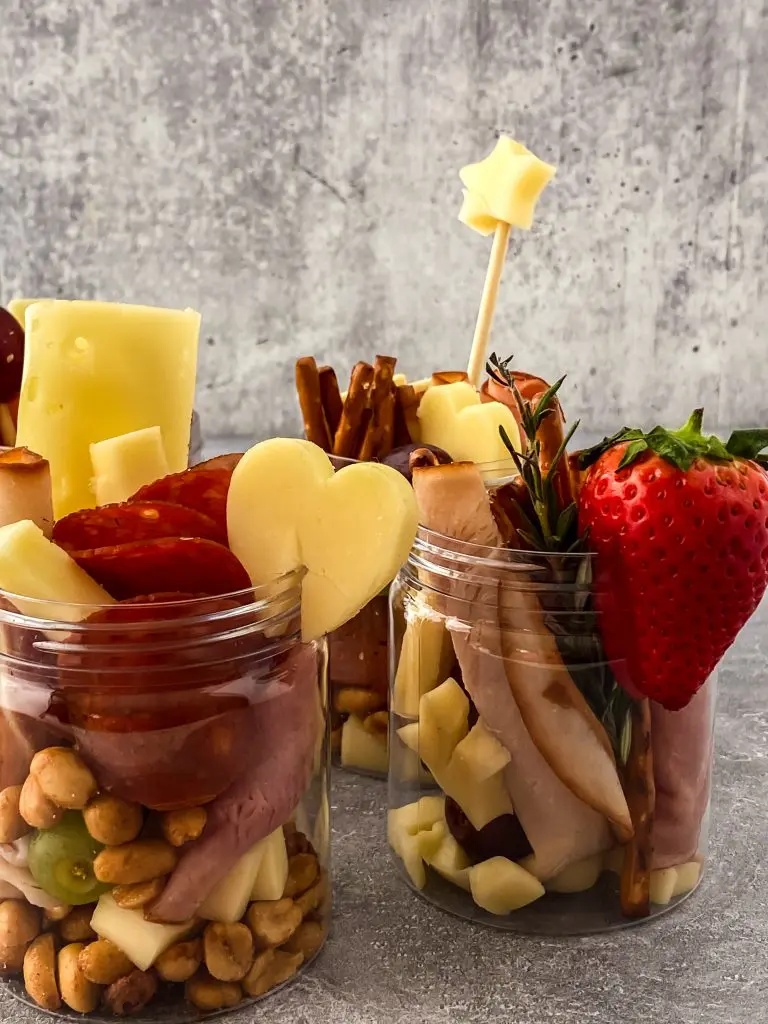 Small jars filled with savory charcuterie ingredients.