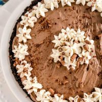 Top down photo of a chocolate pie decorated with whipped cream stars and chocolate shavings