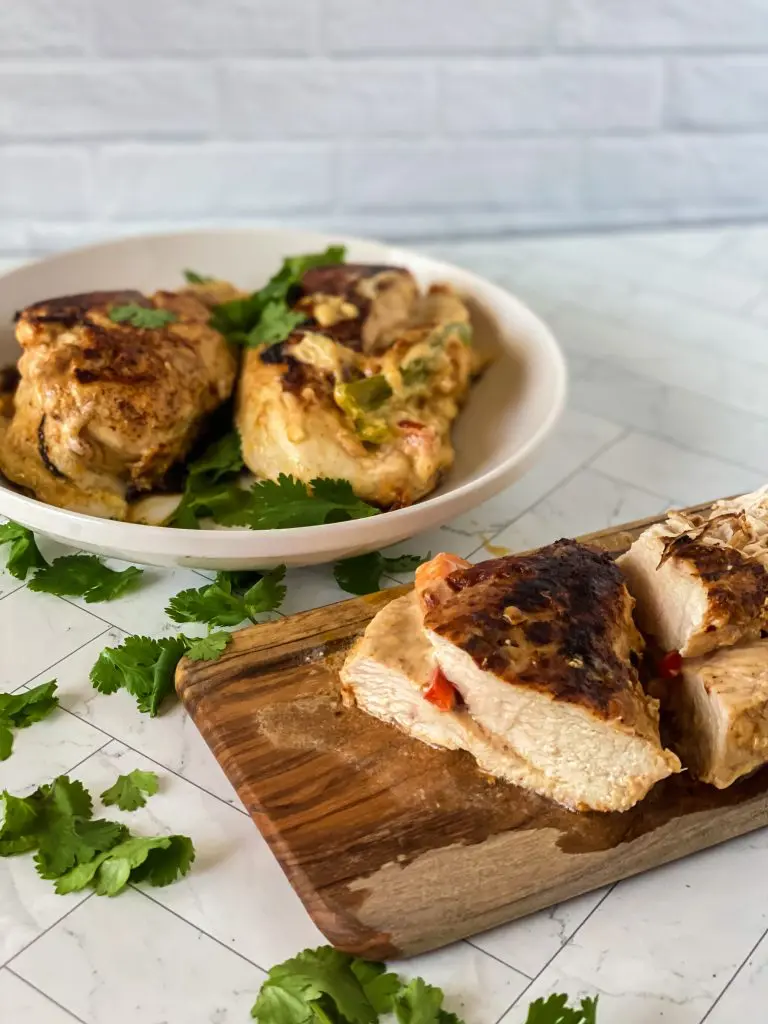 Fajita stuffed chicken on a wooden tray with a plate full of chicken in the background. 