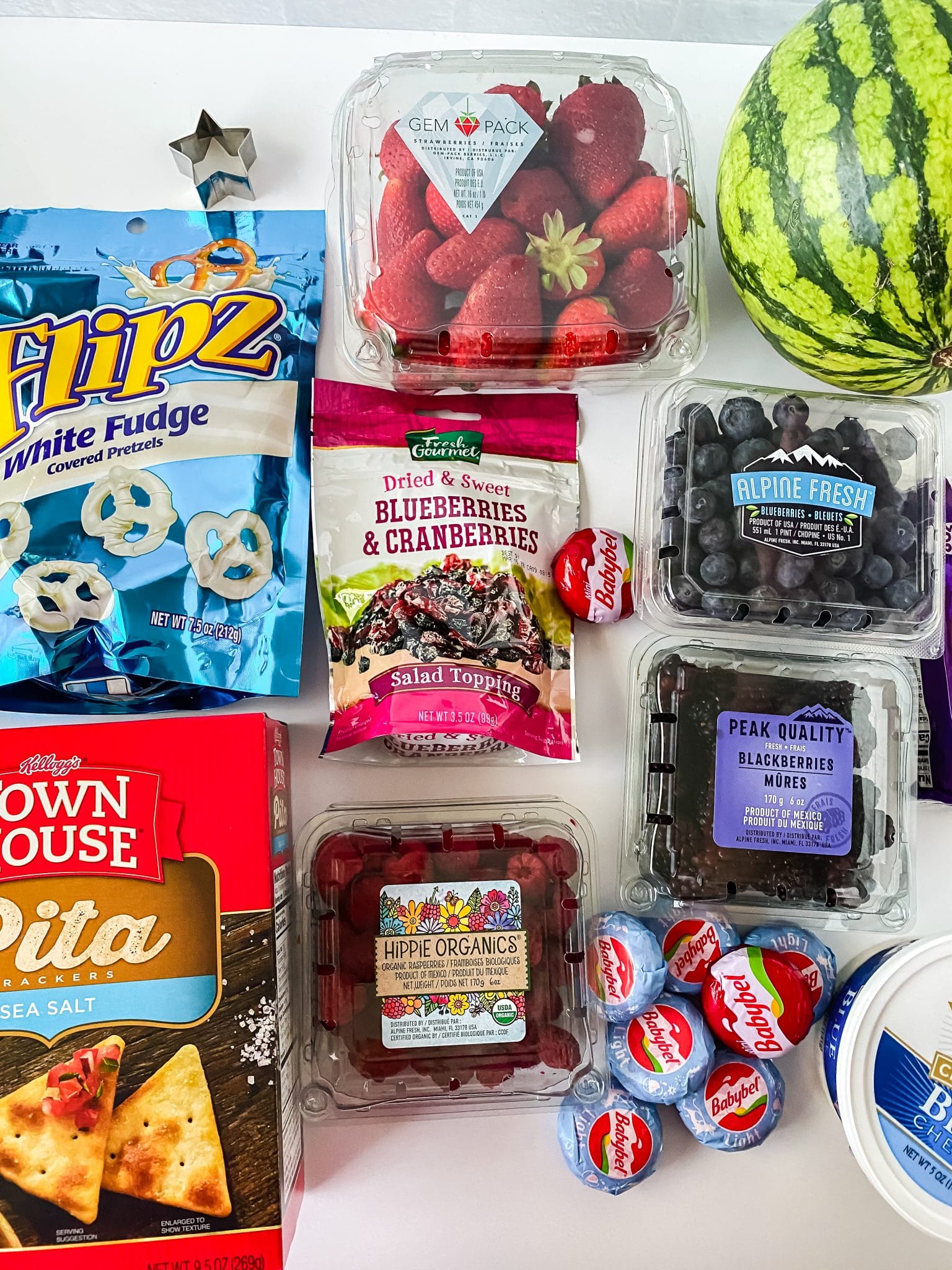 Ingredients used to make a Patriotic Charcuterie  Board including fruits, cheeses, crackers, and pretzels.
