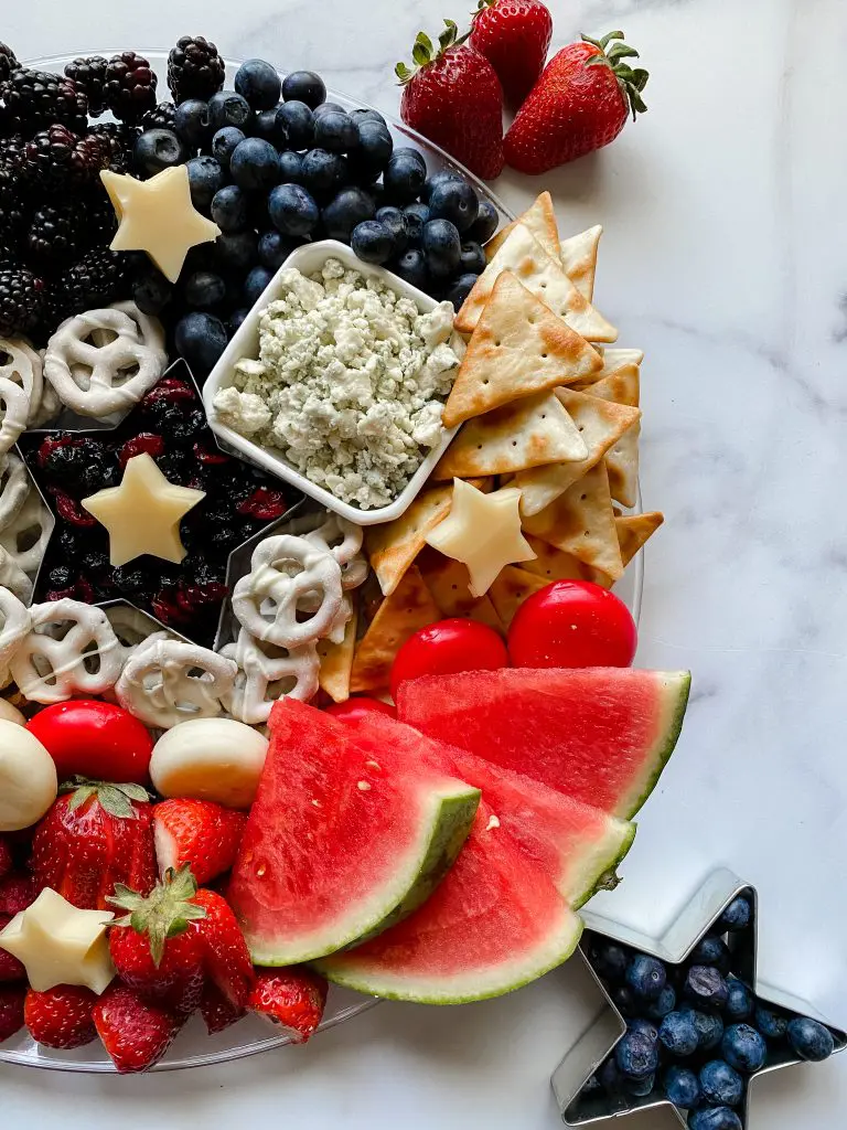 beautiful patriotic charcuterie board with crackers, cheese, and fruit. 