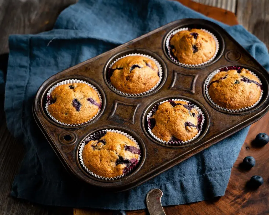 Top down view of a muffin tin filled with baked blueberry muffins