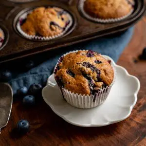 Close up side view of a berry muffin sitting on a white plate