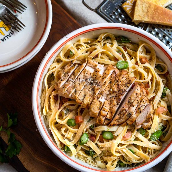Top down photo of a bowl of fettuccine pasta topped with grilled chicken.