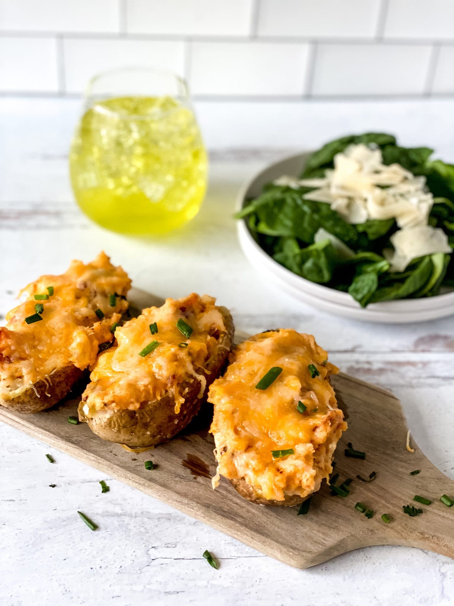 Three Twice-baked potatoes displayed on a cutting board.