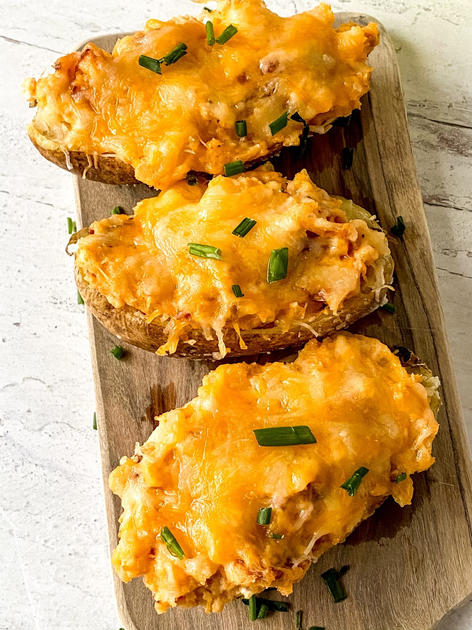 Three twice-baked potatoes on a board close-up.
