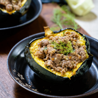 3/4 angle view of one half of a baked acorn squash stuffed with sausage and fennel.