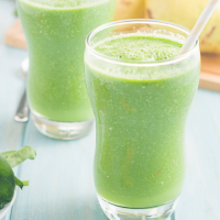 Two glasses of a green smoothie made with pear and ginger.