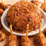Top down photo of a round bacon covered cheeseball surrounded by football shaped mini cheeseballs