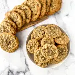 Baked chocolate chip cookies sitting in a bowl and surrounded by a swirl of cookies.